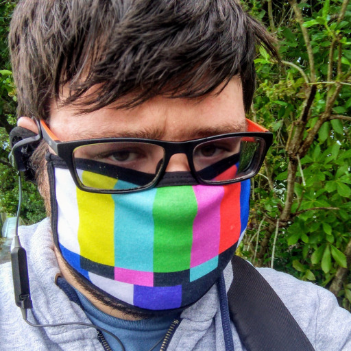 Photo of Dillon in front of green leafy background wearing a colorful mask.
